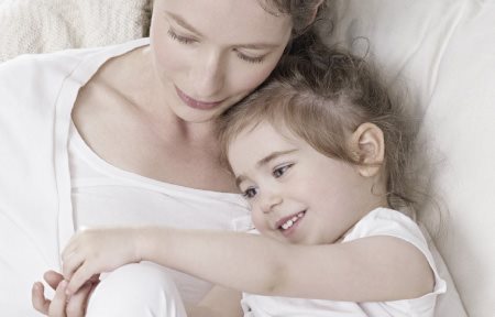 Madre e hija tendidas una al lado de la otra, abrazadas.