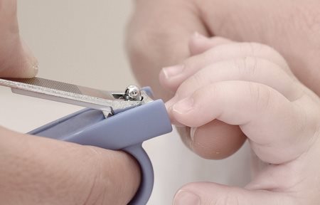 Madre cortando las uñas del niño con un cortauñas.