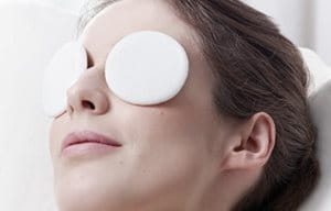 Mujer relajándose con parches fríos en los ojos